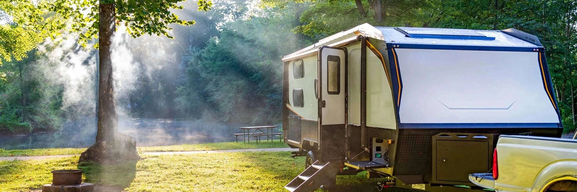 An RV parked at a wooded campsite in morning light