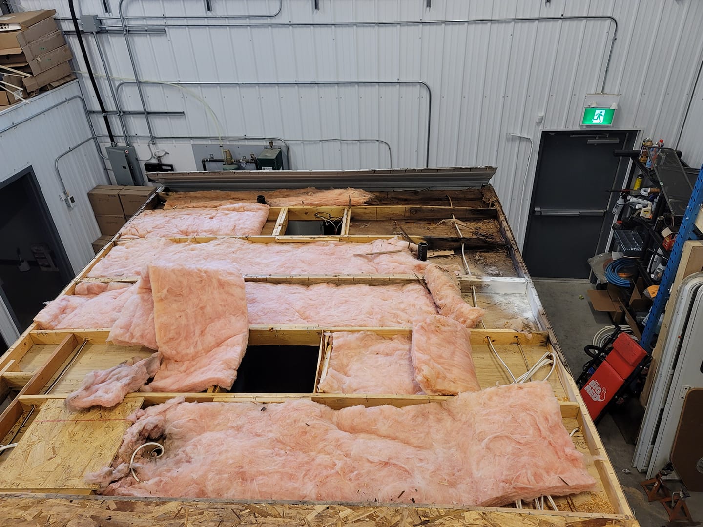 An RV roof stripped to the framing inside the shop, insulation exposed during a rebuild